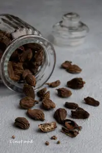 black cardamom spilling out of glass jar
