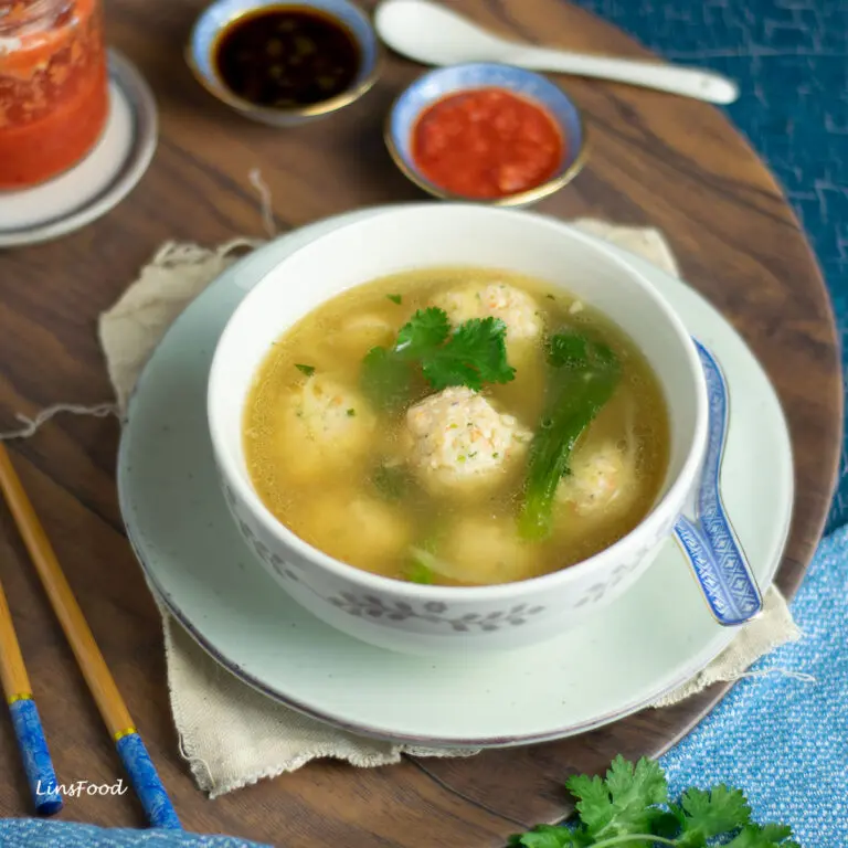 bowl of prawn ball soup with chilli and soy sauce in little bowls