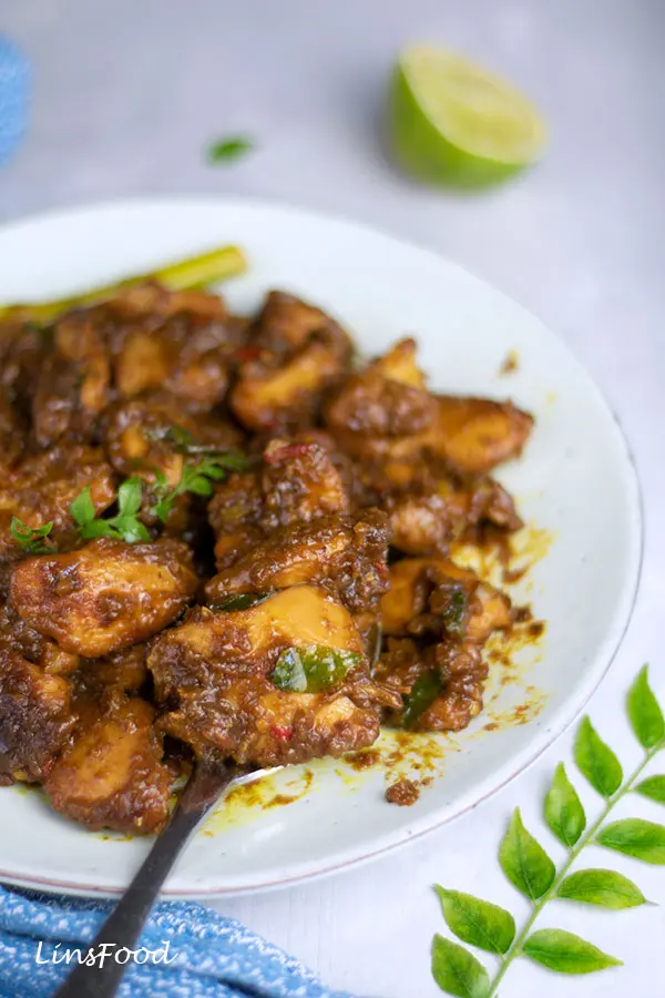 plate of dark stir-fried chicken (kam heong chicken) with lemongrass and curry leaf
