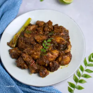 plate of dark stir-fried chicken (kam heong chicken) with lemongrass and curry leaf