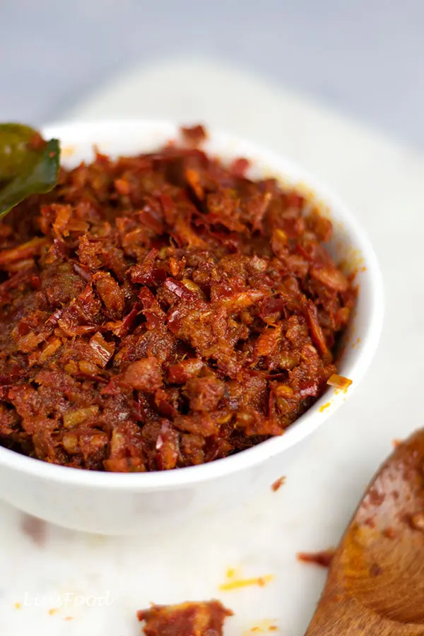 sambal hae bee, spicy dried shrimp condiment in a white bowl with kaffir lime leaf