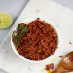 sambal hae bee, spicy dried shrimp condiment in a white bowl with kaffir lime leaf