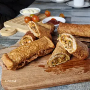roti sardin goreng, fried sardine rolls on a wooden board with sauces in the background