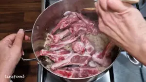 Bone-in lamb chops being browned with the onion, garlic and ginger paste.