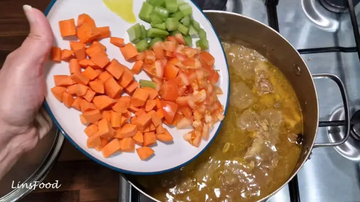 Chopped carrot, tomato and celery being added to the simmering sup kambing.