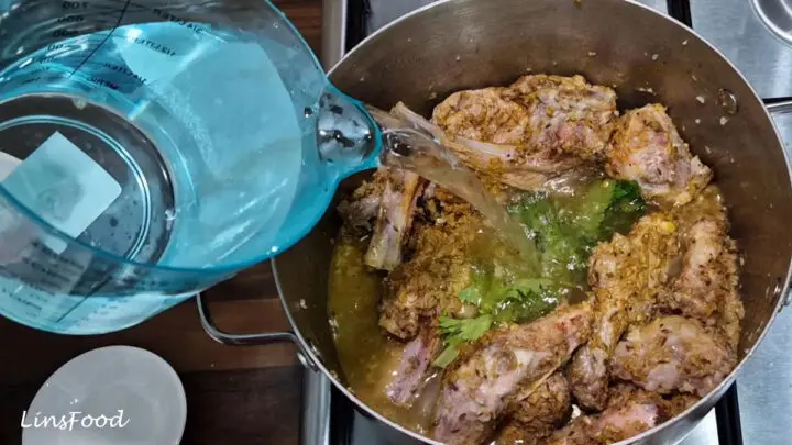 Water being poured over the spiced lamb and bones for sup kambing.