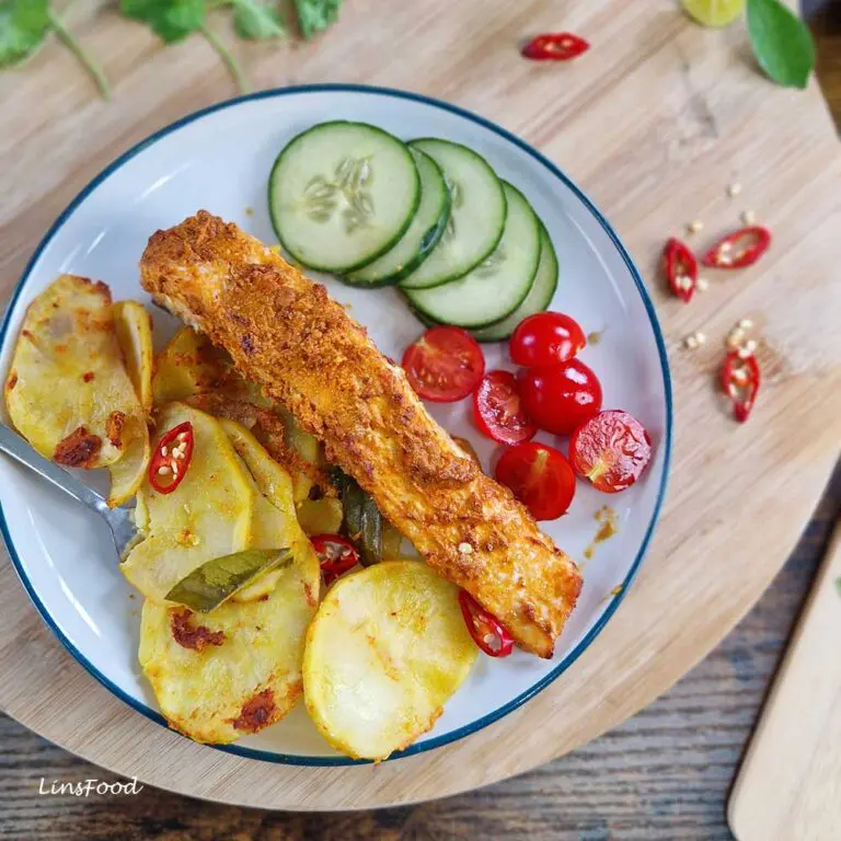 Overhead plate of ikan bakar salmon traybake with turmeric potatoes, cucumber and tomatoes.
