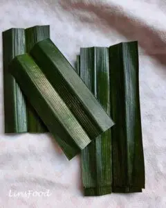 Fresh pandan leaves cut into short pieces on a cloth