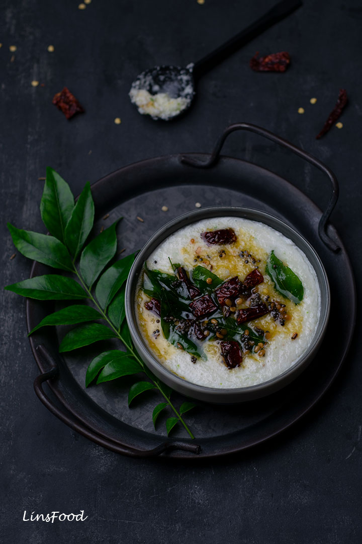Coconut chutney in a grey bowl, topped with dried red chillies and curry leaves