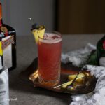 singapore sling in a tall collins glass with a pineapple on a cocktail stick