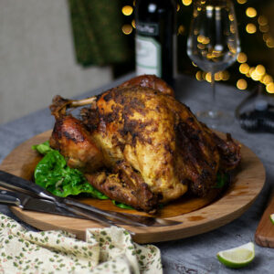 rendang roast turkey on a wooden board with wine bottle and Christmas lights in background