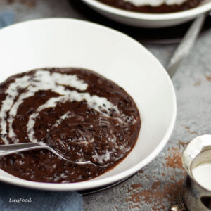 bubur pulut hitam (black rice pudding) topped with coconut milk in white bowl
