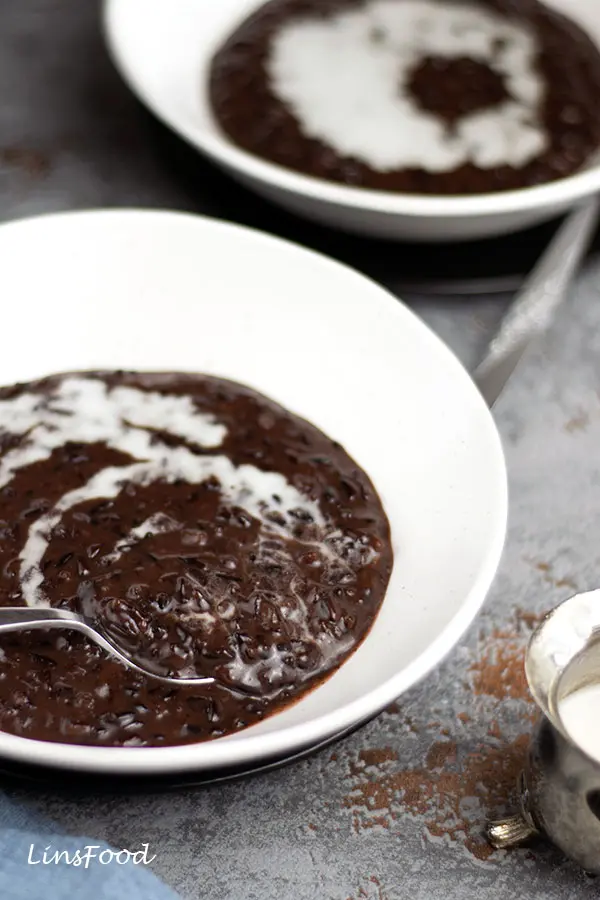 black rice pudding topped with coconut milk in white bowl