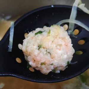 cooked homemade prawn ball in black slotted spoon
