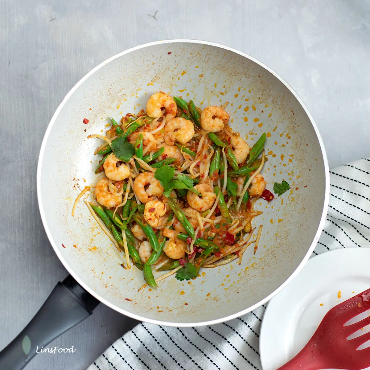 white wok filled with stir-fried prawns (shrimp, green beans and beansprouts
