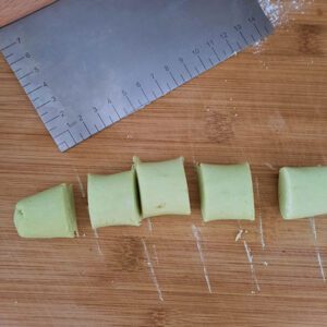 cut green coloured dough on chopping board