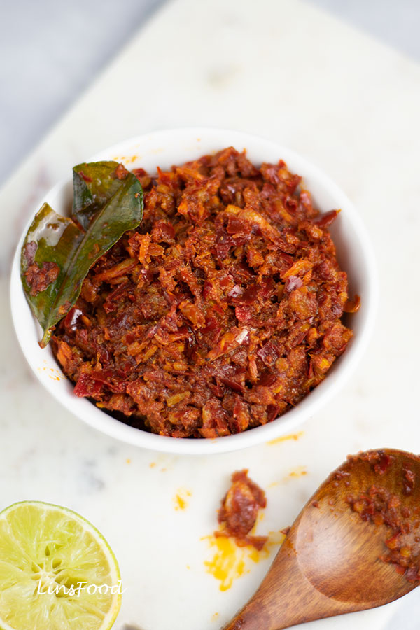 sambal hae bee, spicy dried shrimp condiment in a white bowl with kaffir lime leaf