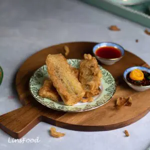 pisang goreng, or goreng pisang, fried banana fritters on a side plate, on a wooden board with 2 dips on the side