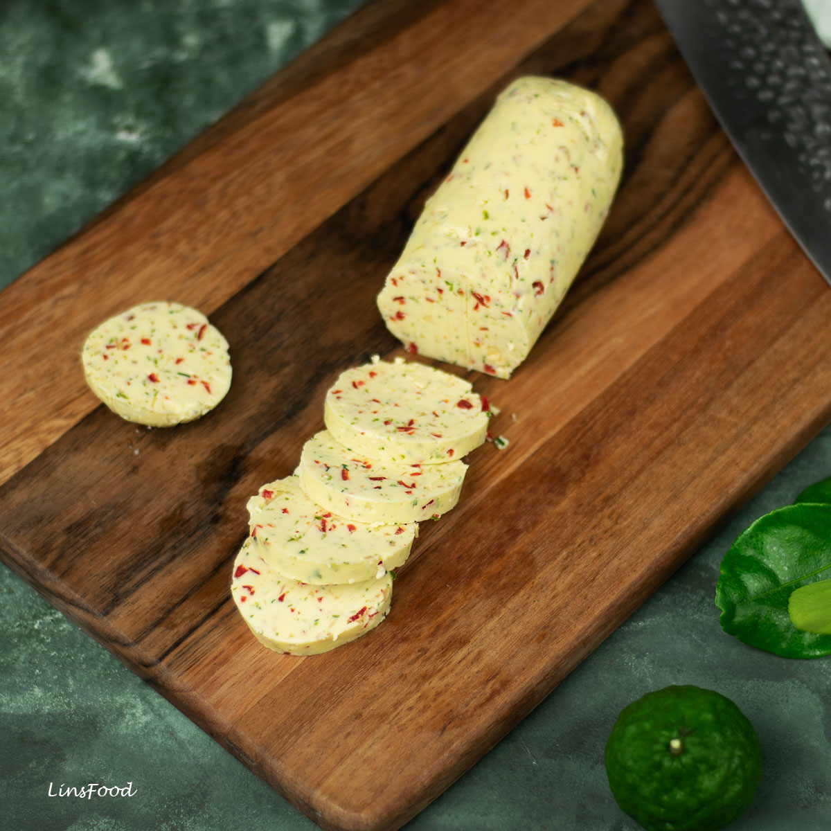 flavoured butter (chilli butter) log, with sliced pieces on wooden chopping board