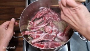Bone-in lamb chops being browned with the onion, garlic and ginger paste.