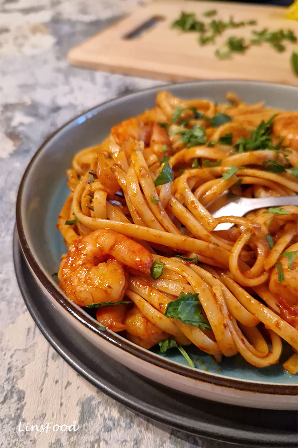 Fork twirling sambal prawn pasta with prawns and herbs.
