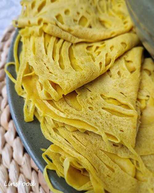 Close-up of vegan roti jala folded and layered on a plate.
