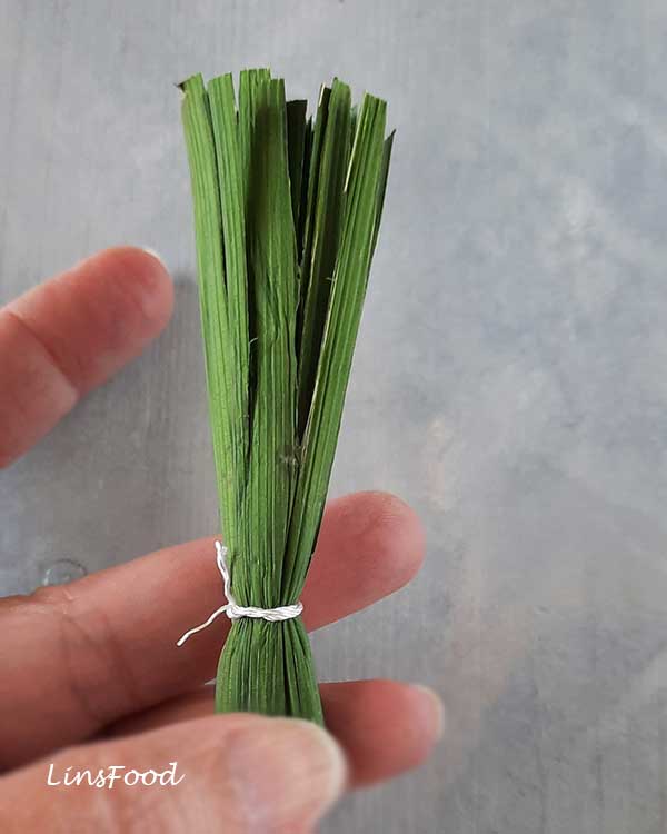 Alt Text
A small brush made from tied pandan leaves held by hand