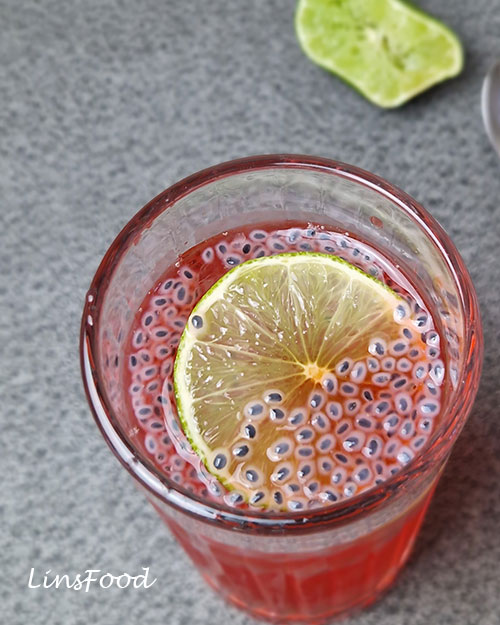 Close-up of soaked basil seeds and a lime slice in pink sirap limau selasih.