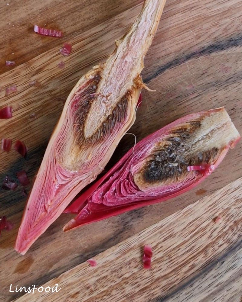 Bunga kantan cut lengthways to show the layered pink bracts and fibrous interior of the torch ginger flower.