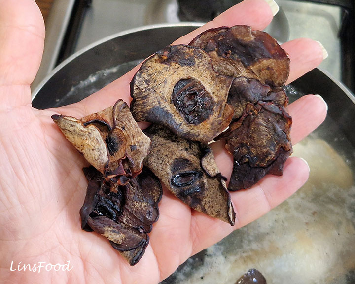 Dried asam gelugur slices held above the saucepan for asam laksa