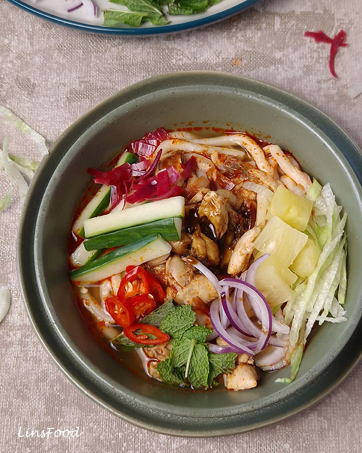 Close-up of Penang asam laksa with mackerel, pineapple, cucumber, mint and chilli