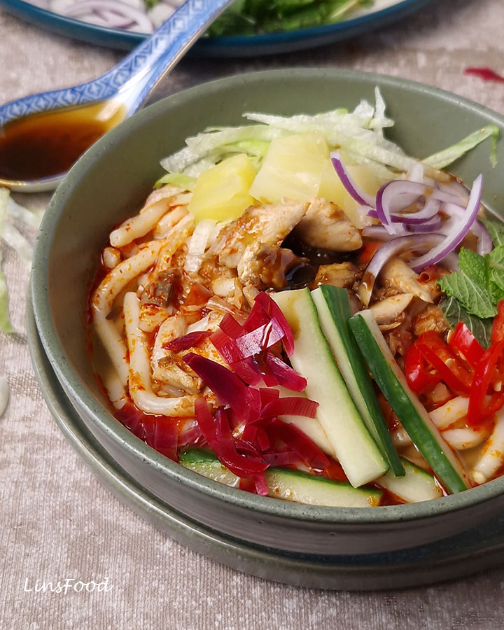 Penang asam laksa topped with pineapple, cucumber, onion, chilli, mint and bunga kantan