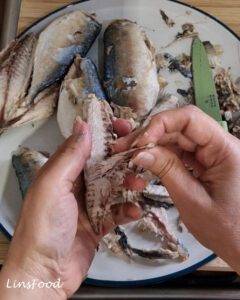 Removing the bones from cooked mackerel for Penang asam laksa