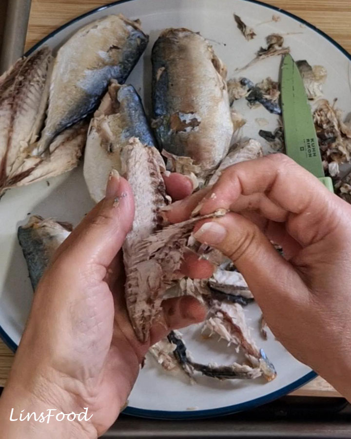 Removing the bones from cooked mackerel for Penang asam laksa